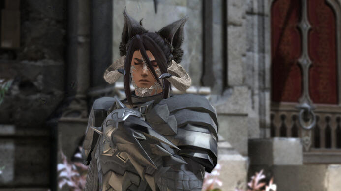 Cinnamon, a Miqo'ra with long dark brown hair and tan skin, looking solumn as they stand in front of the Fortemps Manor, wearing their Dark Knight attire.